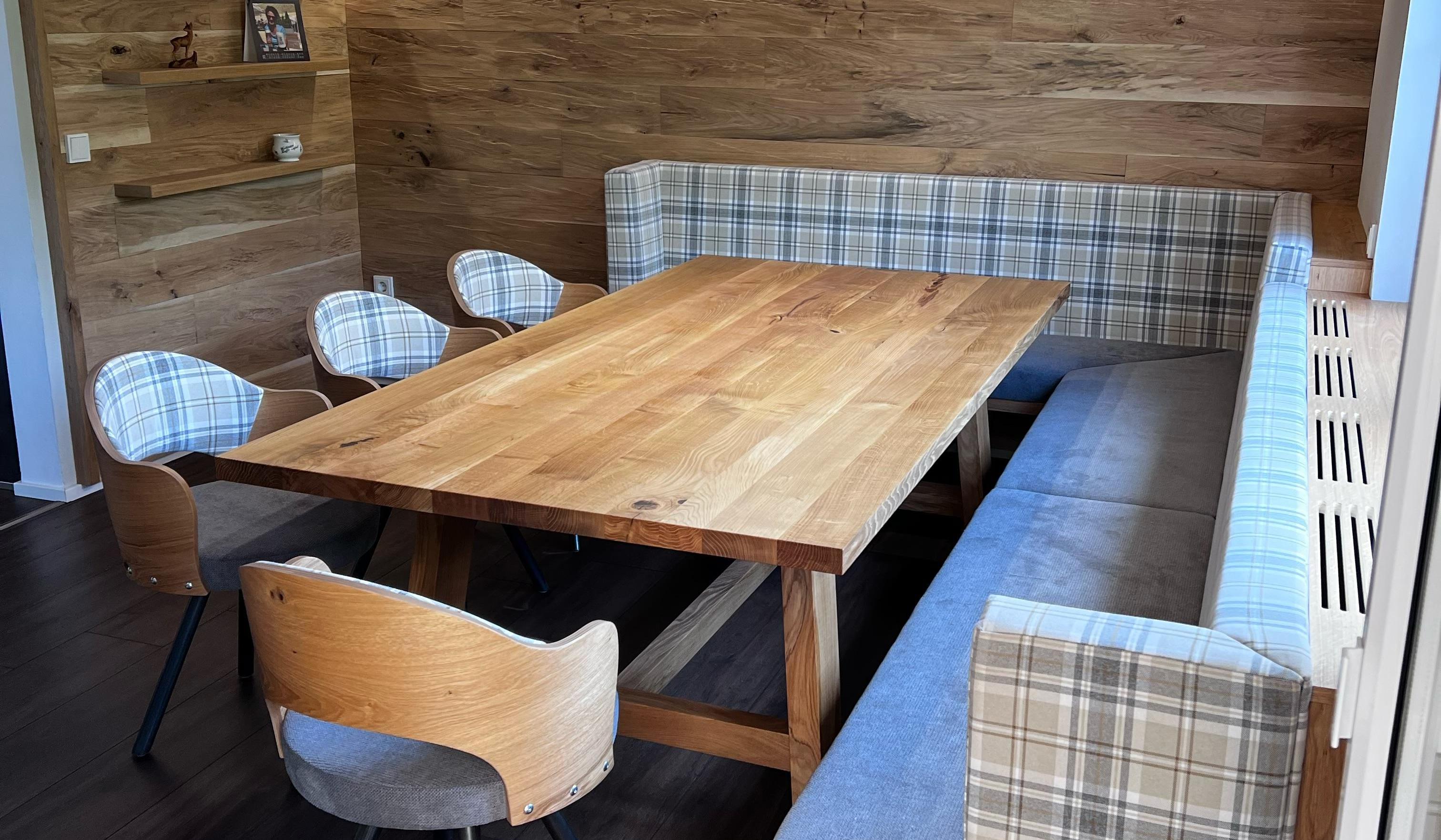 Gemütliche Essecke mit Holztisch, Eckbank und modernen Stühlen, Holzwand im Hintergrund.