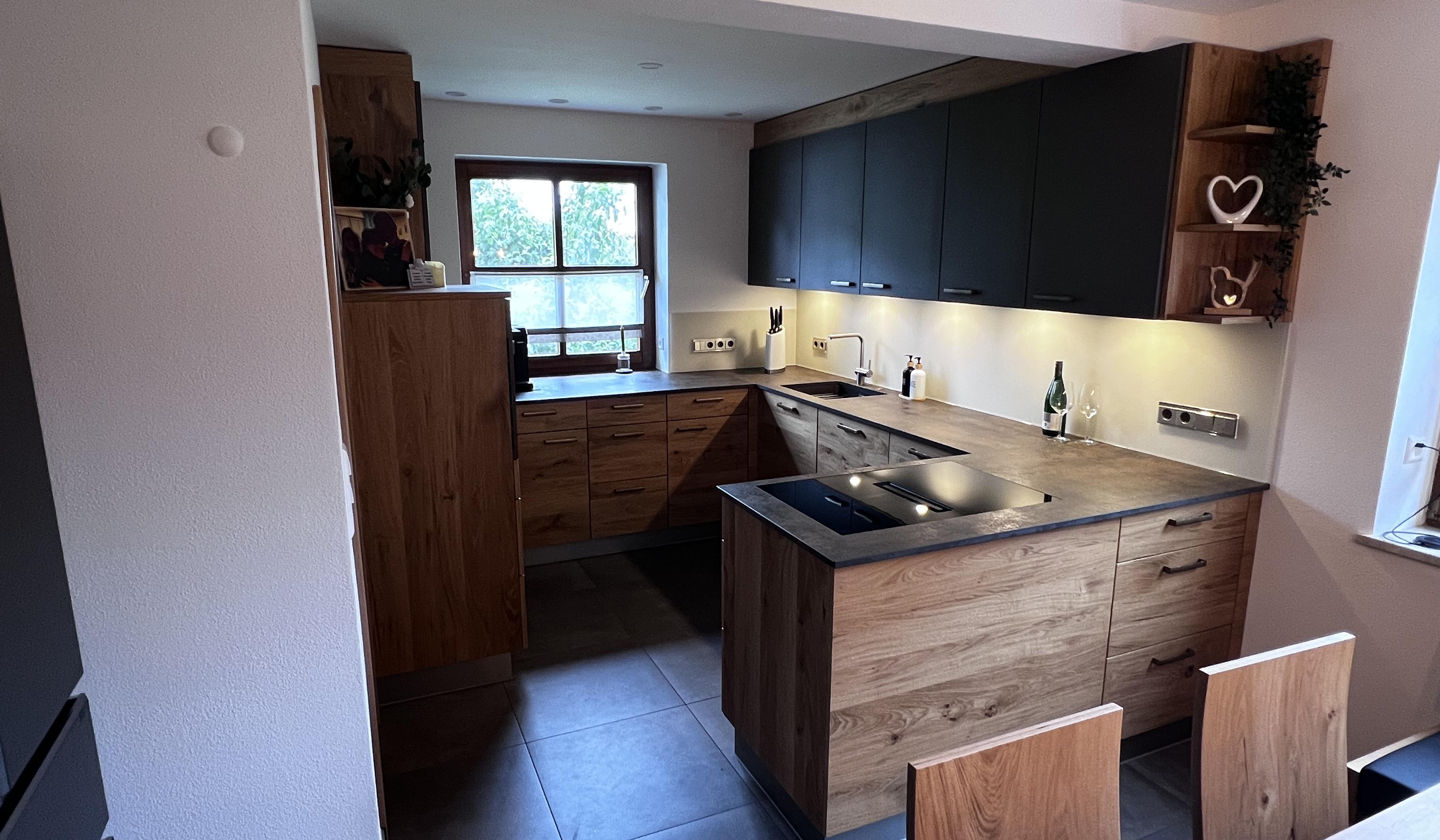 Moderne Küche mit Holzfronten, dunklen Oberschränken und großem Fenster.
