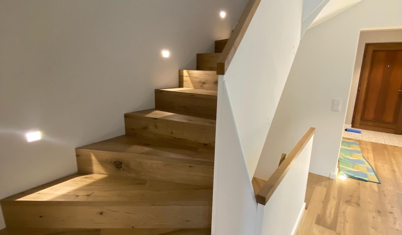 Holztreppe in modernem Haus mit eingebauten Wandlichtern.