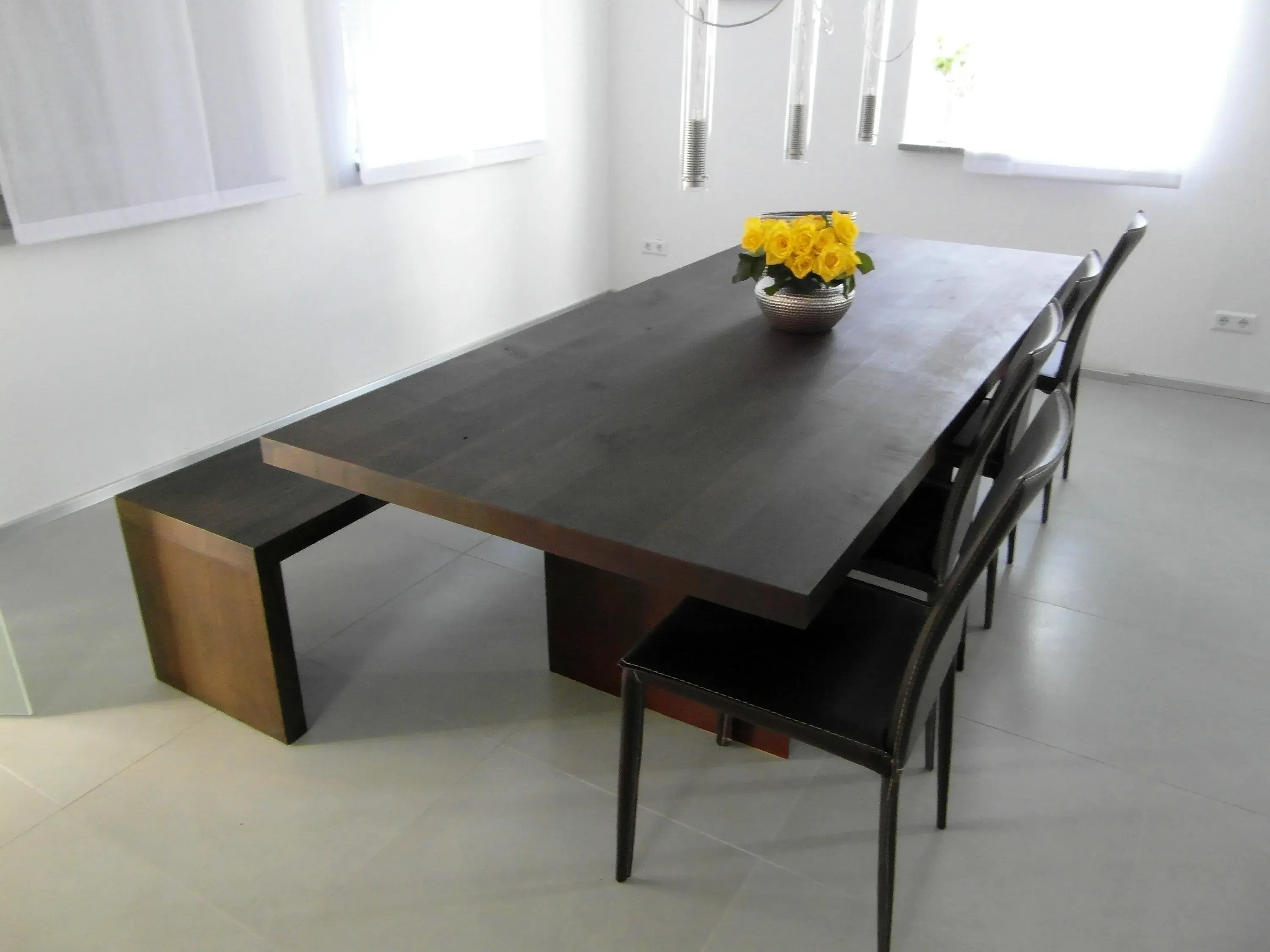 Großer Holztisch mit schwarzem Stuhl, gelbe Blumen als Dekoration, modernes Esszimmer.