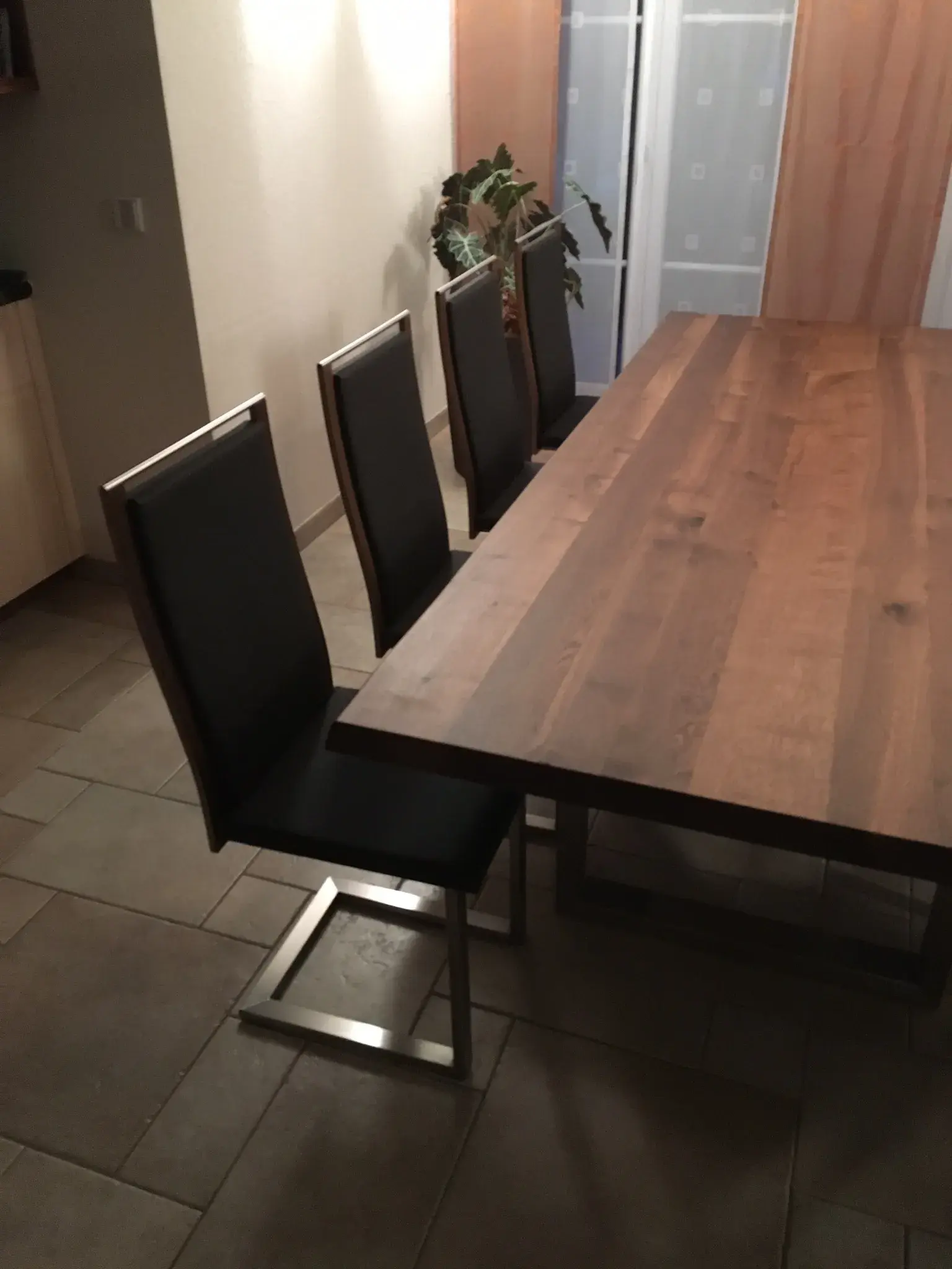 Großer Holztisch mit drei modernen, schwarzen Stühlen in einem Esszimmer.