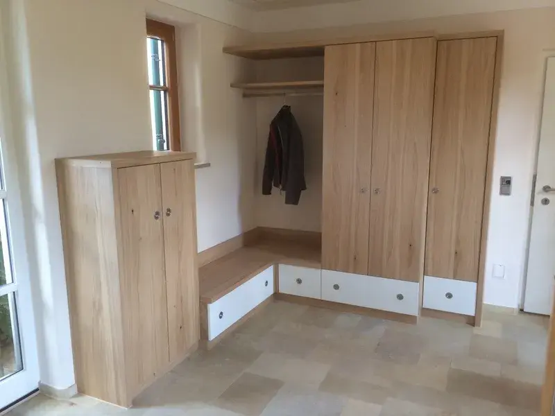 Garderobe in hellem Holz über Eck mit Sitzbank