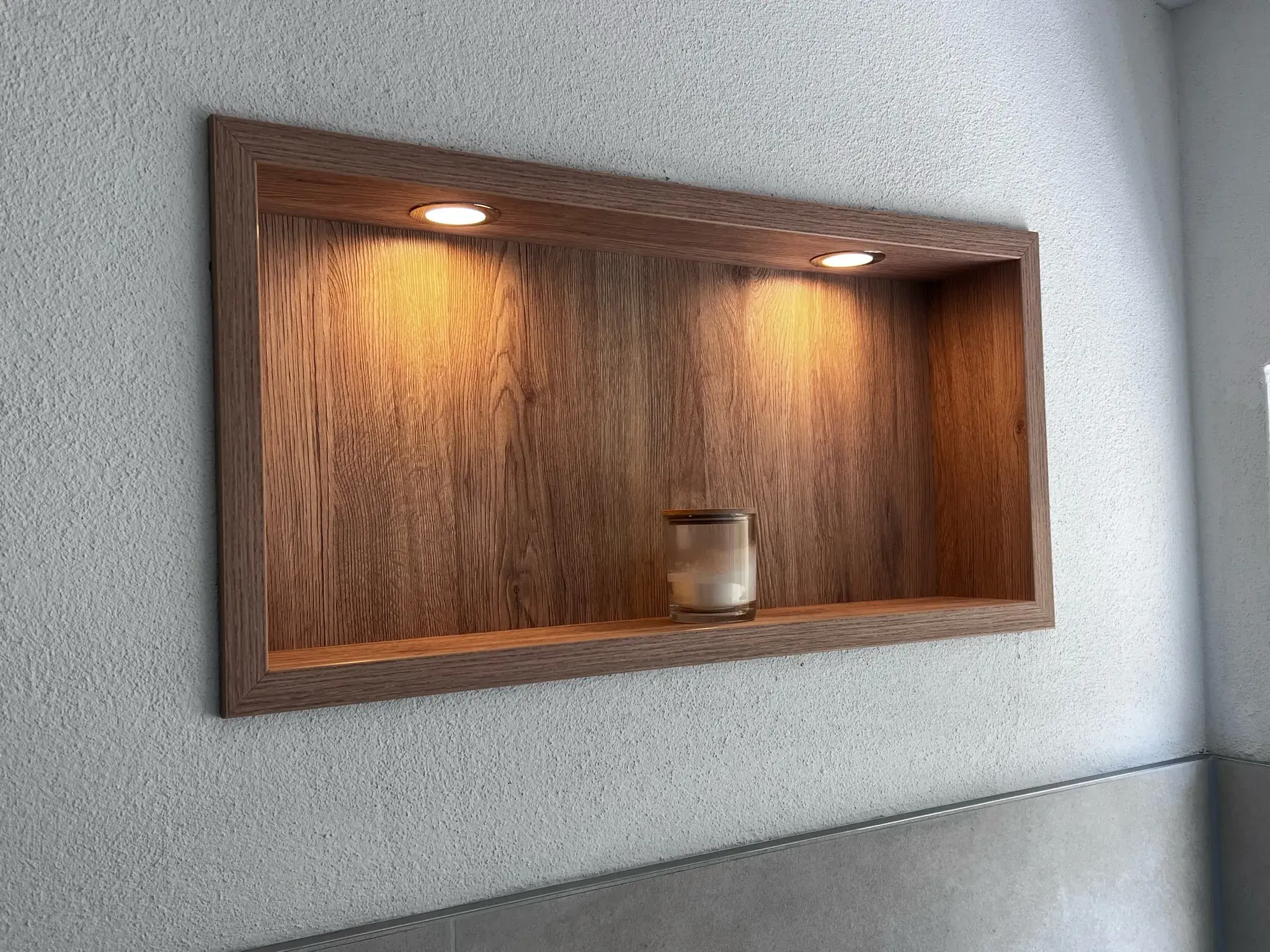 Holzregal mit zwei Spotlichtern und einer kleinen Glasvase auf einem Brett.