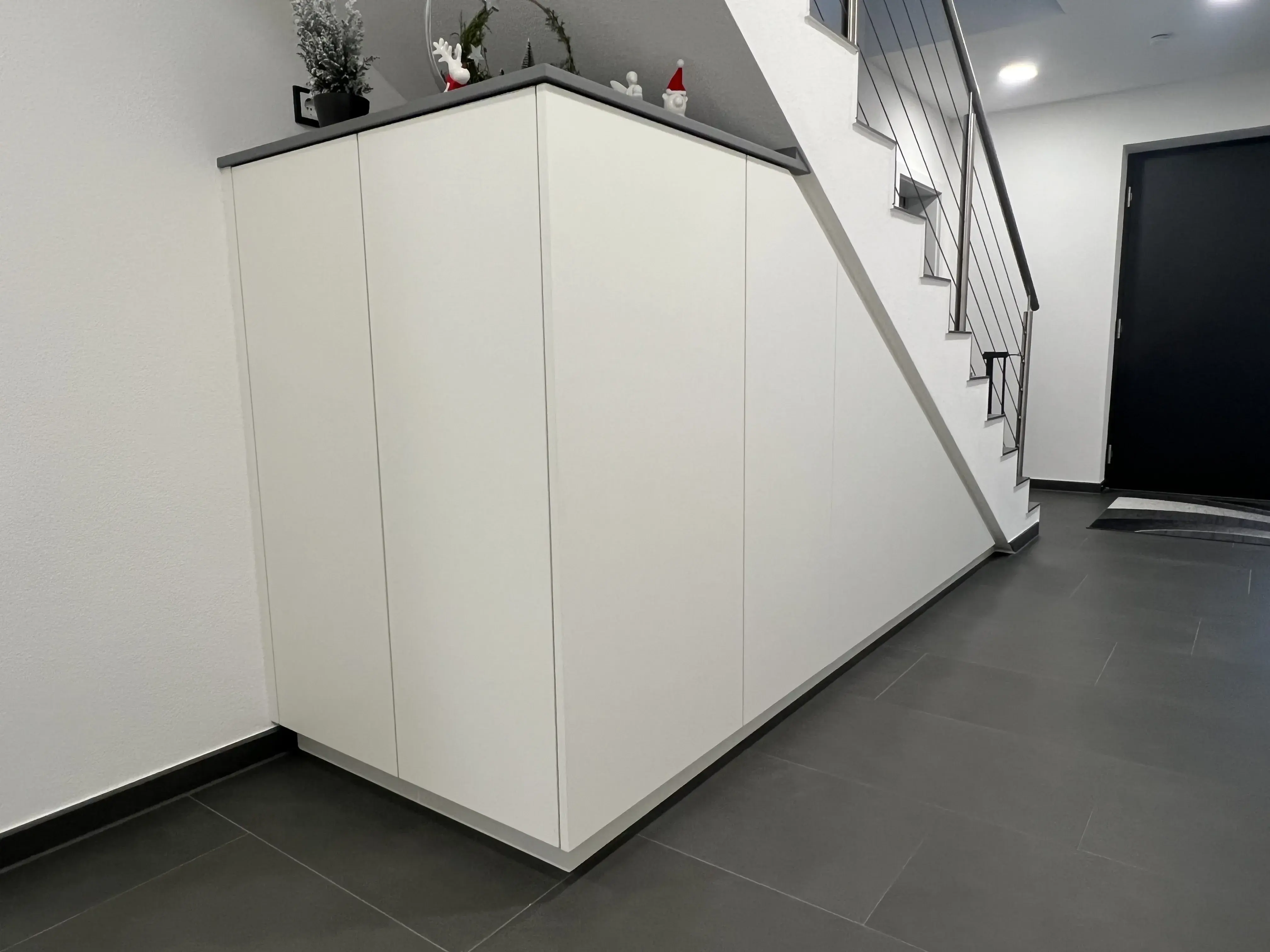 Weißer Einbauschrank unter einer Treppe in modernem Flur.