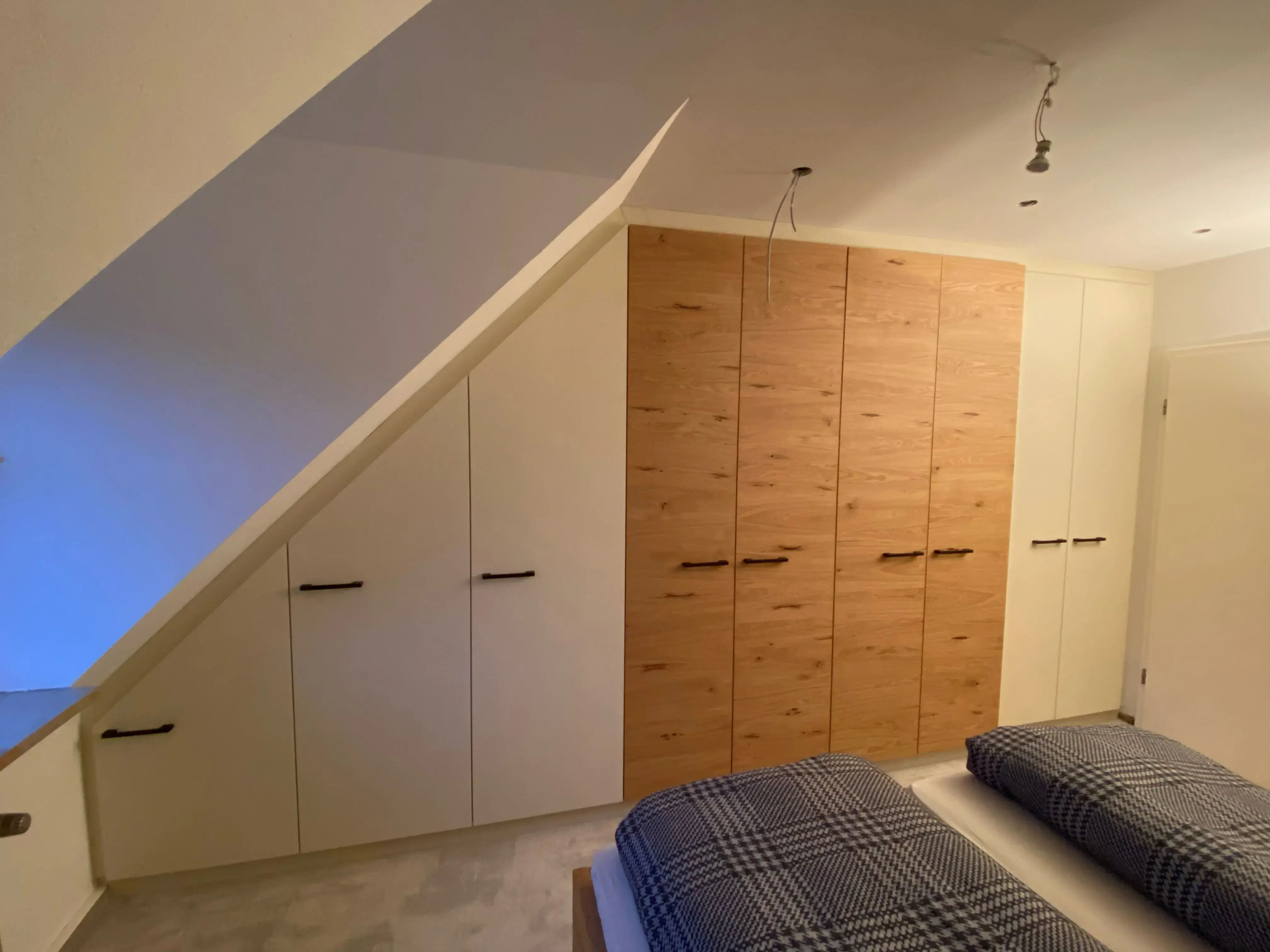 Modernes Schlafzimmer mit Einbauschränken und zwei Betten mit karierten Decken.