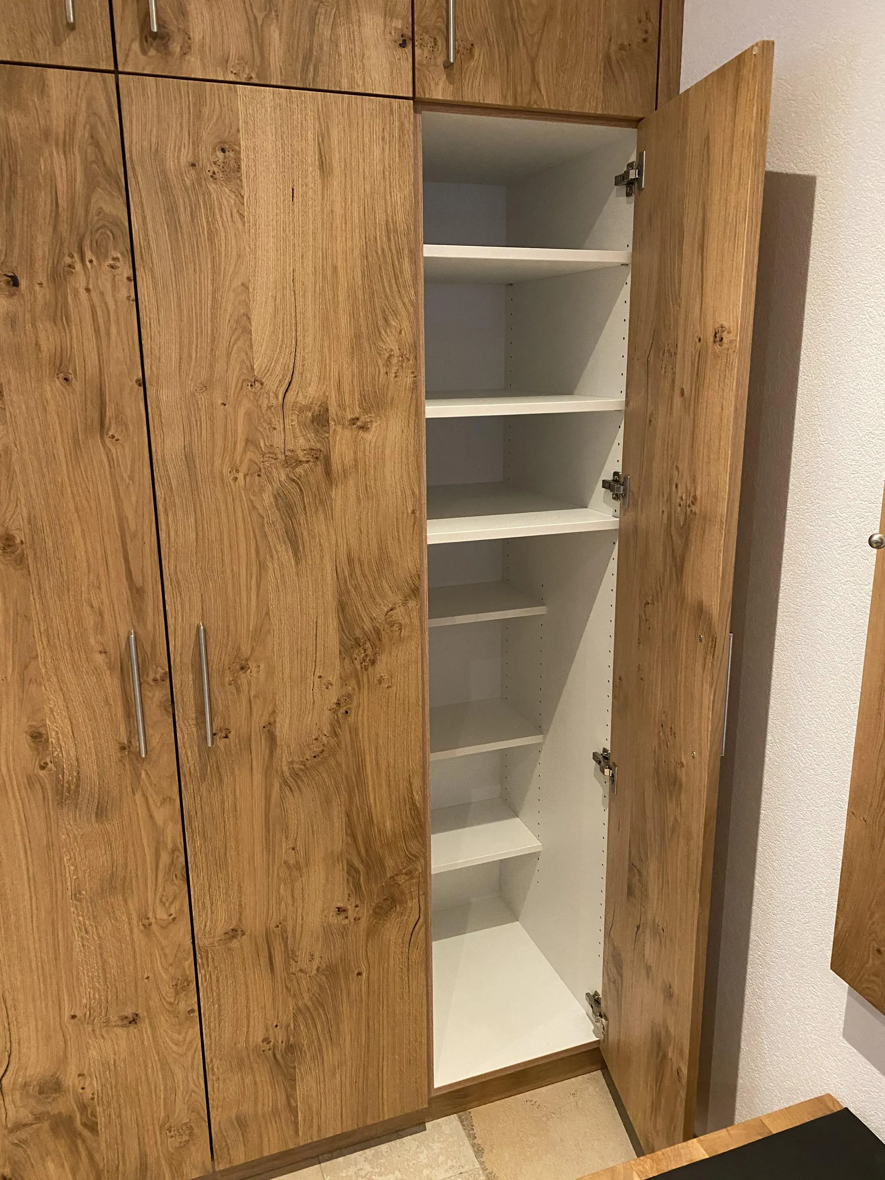 Geöffneter Holzschrank mit weißen Regalböden im Inneren