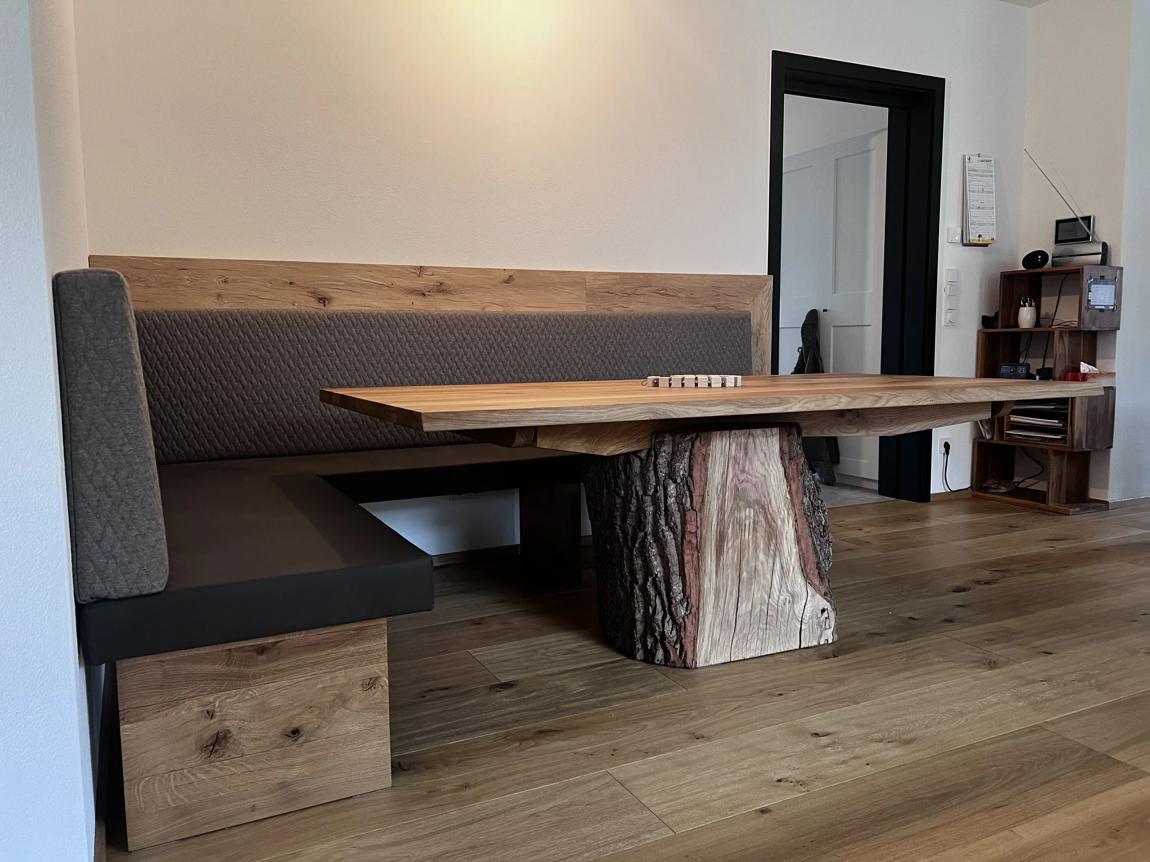 Ecke mit Holzbank und großem Holztisch auf Parkettboden, moderne Einrichtung.
