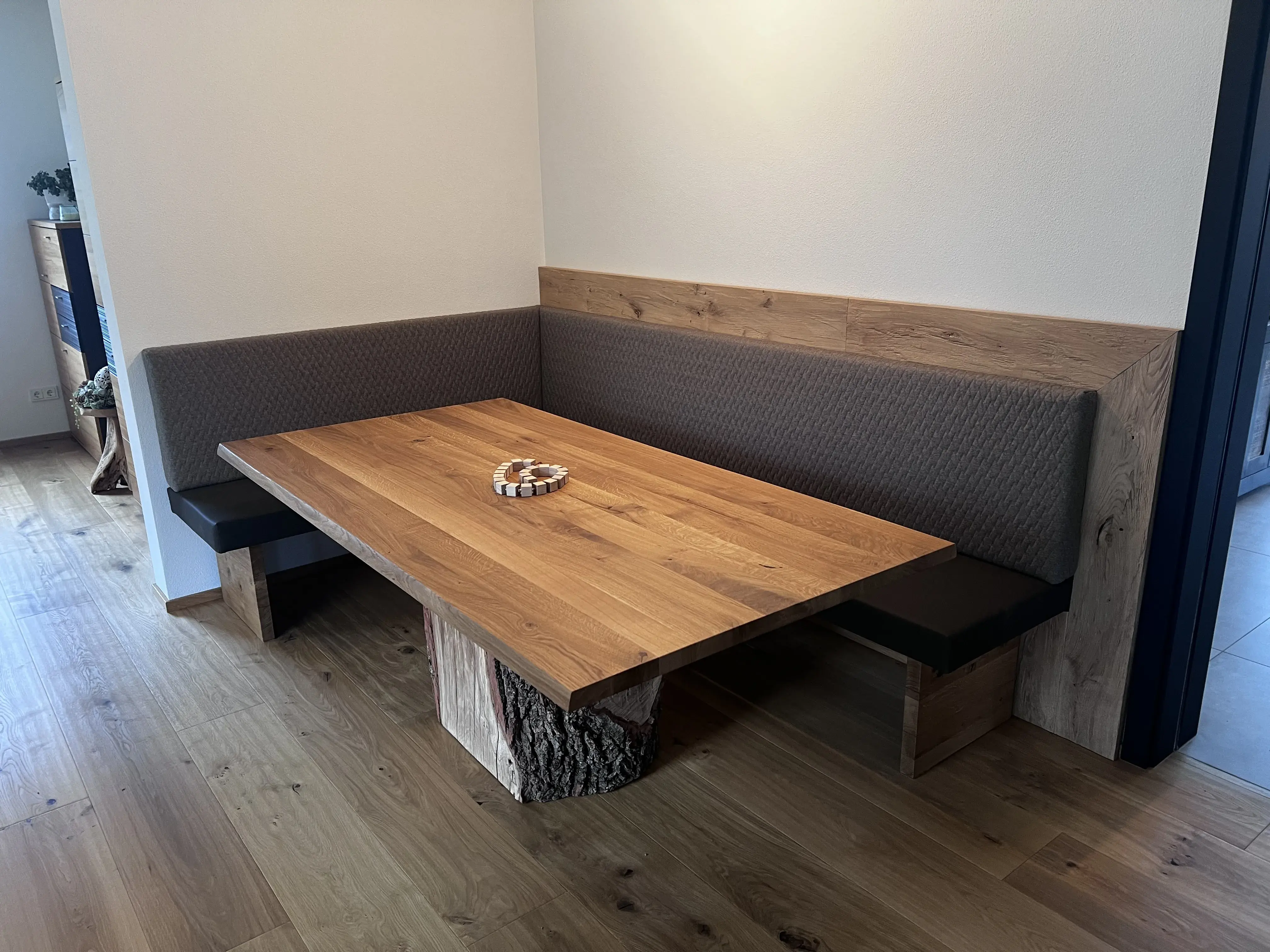 Holztisch mit gepolsterter Eckbank in modernem Essbereich, Dekoration auf dem Tisch.