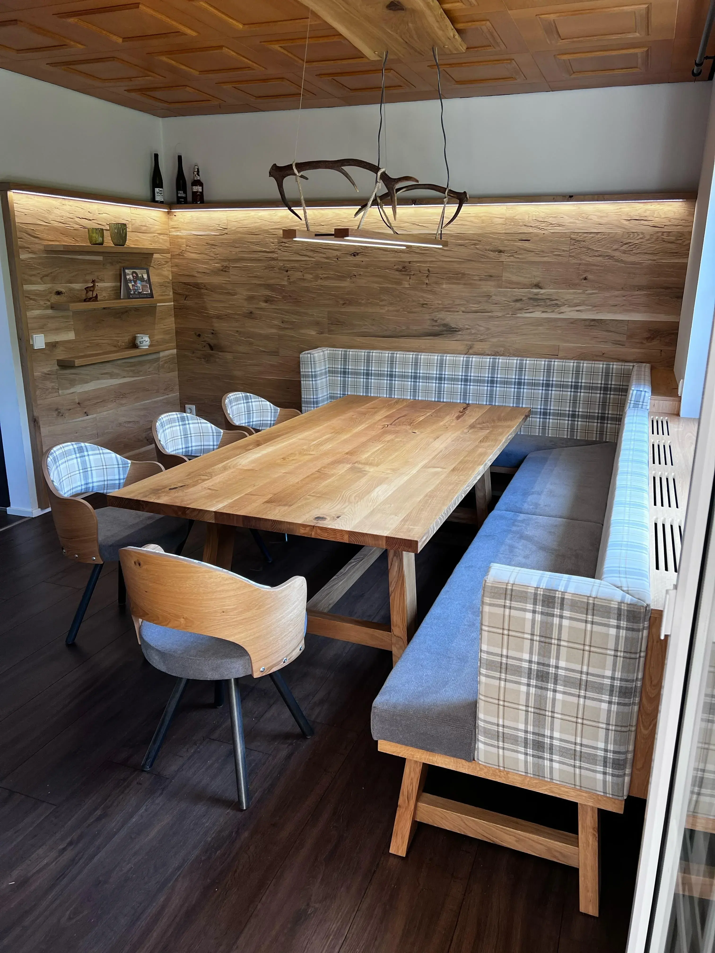 Gemütliche Essecke mit Holztisch, Eckbank und modernen Stühlen, Holzwand im Hintergrund.
