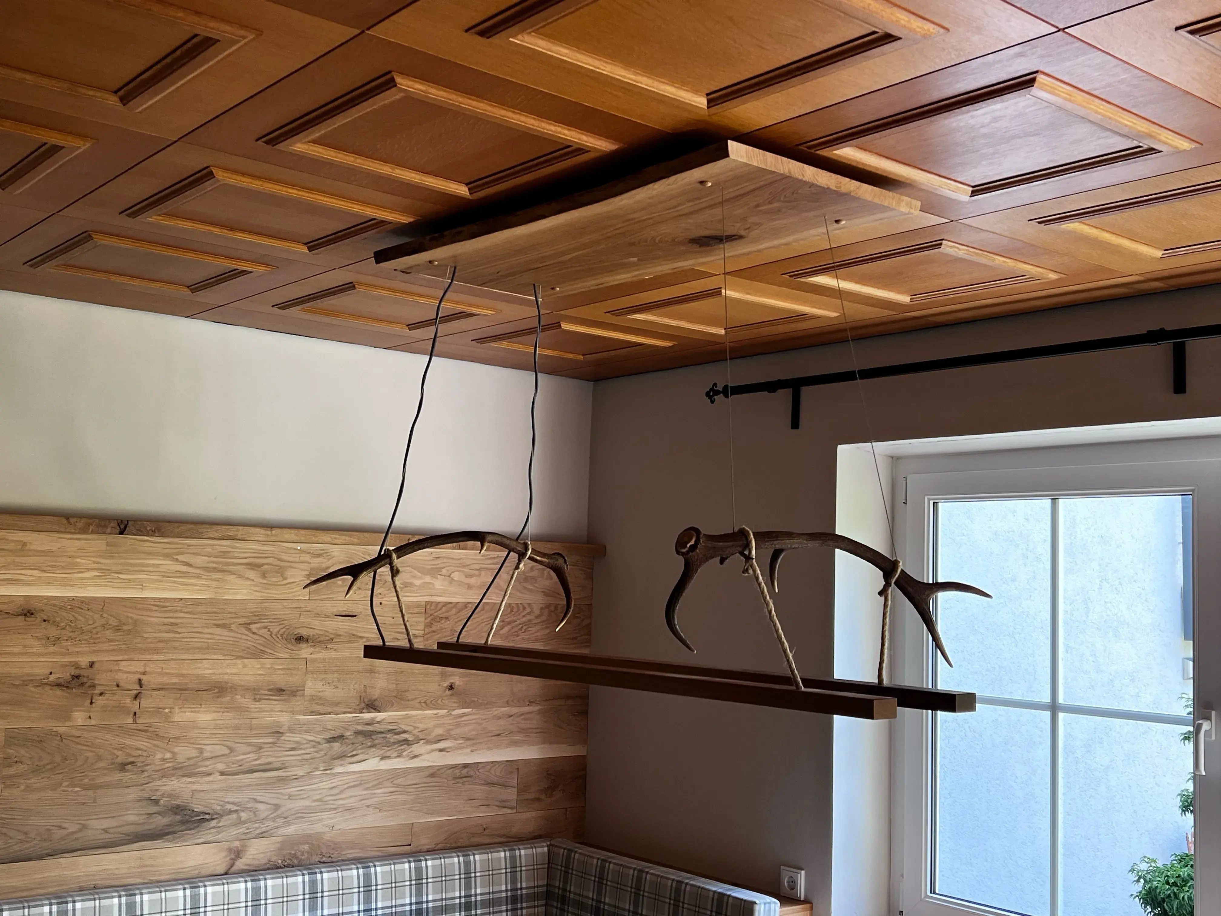 Holzlampe mit Rehfiguren hängt an einer Holzdecke in einem gemütlichen Zimmer.