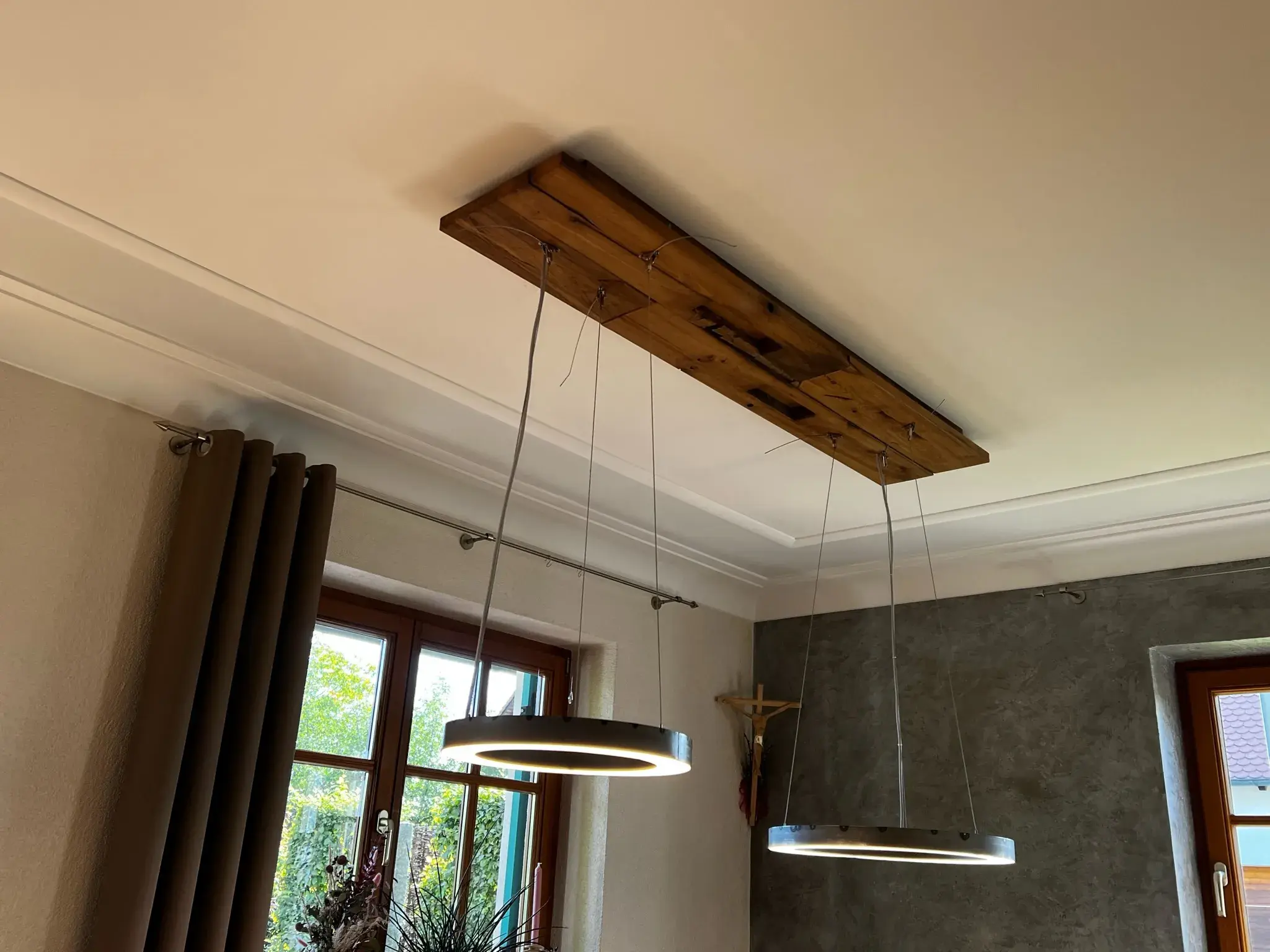 Moderne Hängelampen an Holzplatte, helle Decke, Fenster im Hintergrund