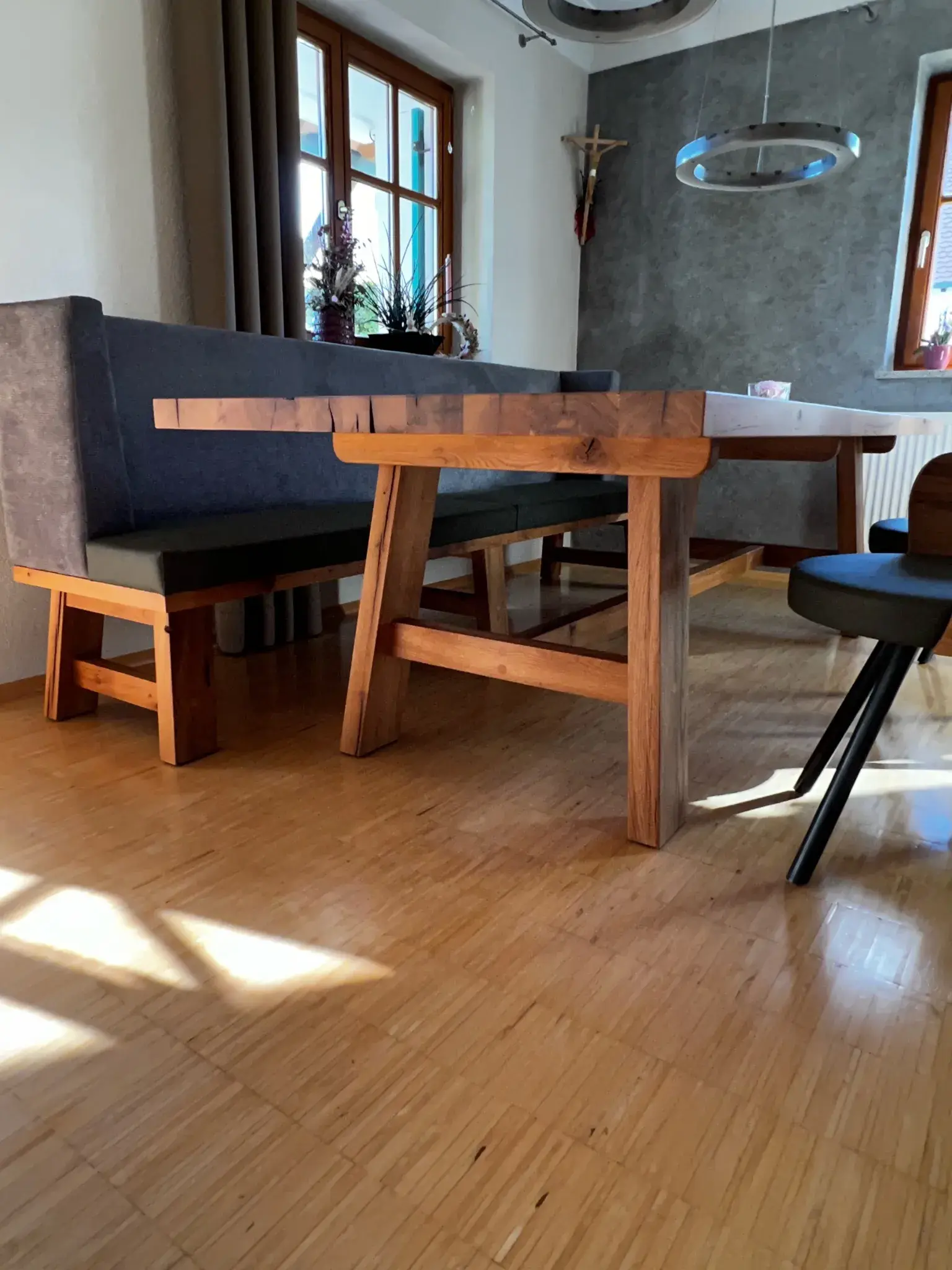 Holztisch mit Bank und Stühlen in einem sonnigen Esszimmer mit Holzboden.