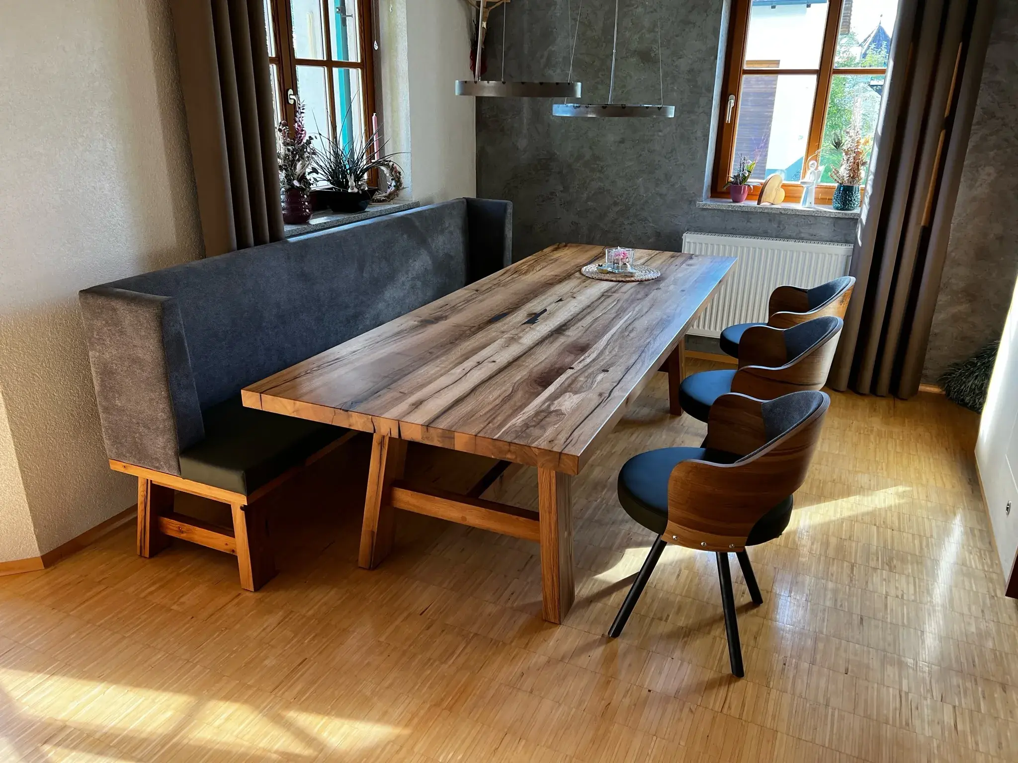 Holztisch mit Bank und drei Stühlen in modernem Esszimmer mit Holzboden.