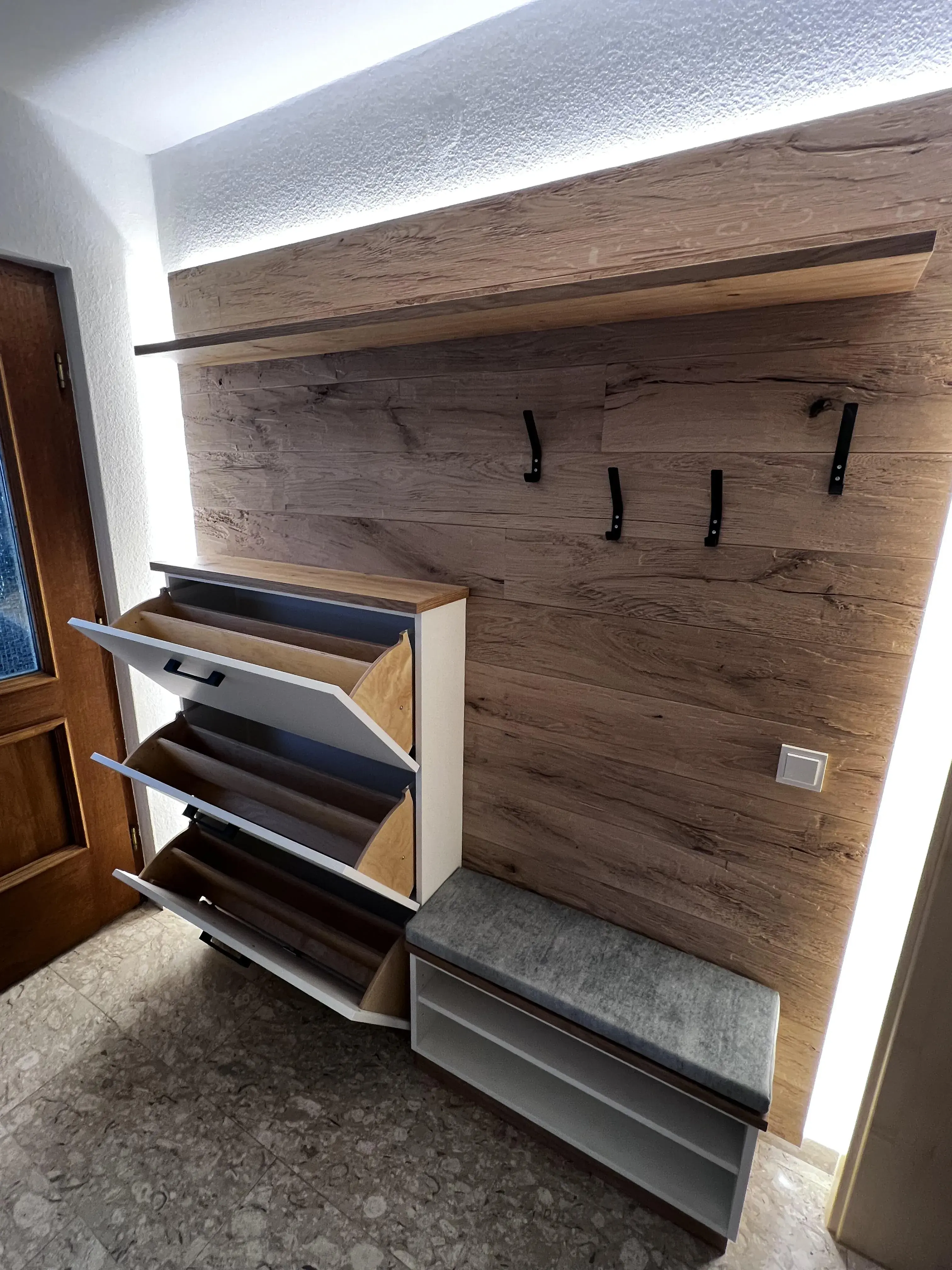 Moderner Flur mit Holzpaneel, offenen Schuhschränken, Bank und Haken für Jacken.