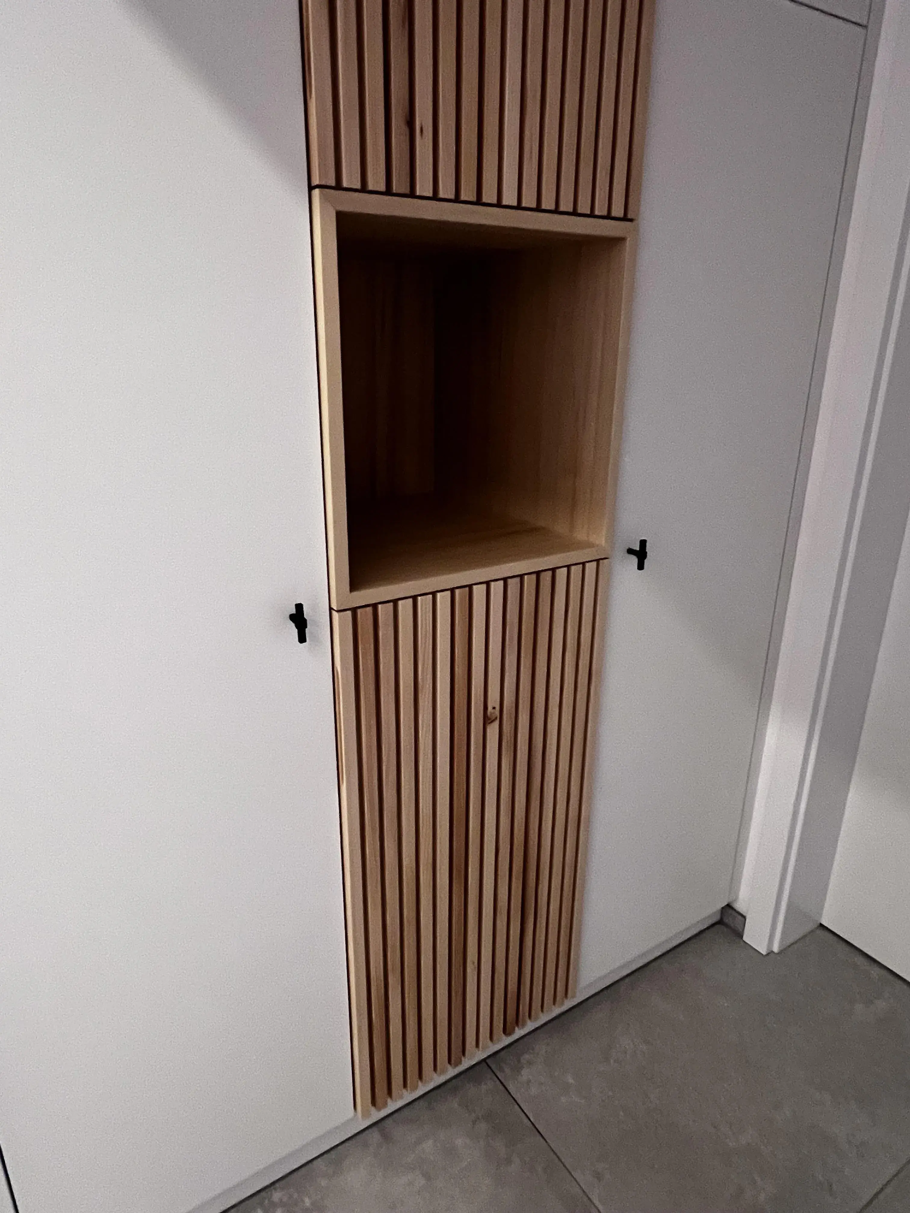 Weißer Einbauschrank mit Holzvertäfelung und offenem Regalbereich.