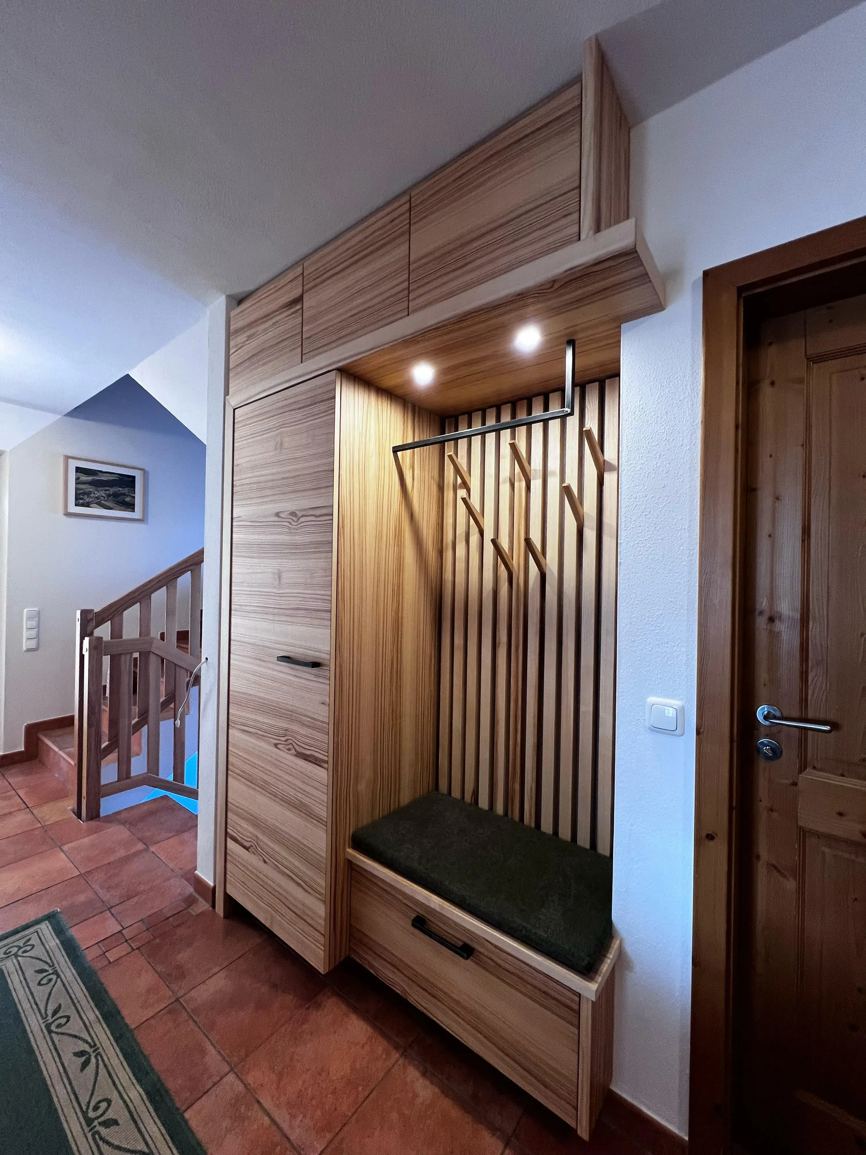Flur mit Garderobe aus Holz, Sitzbank, Haken und Beleuchtung