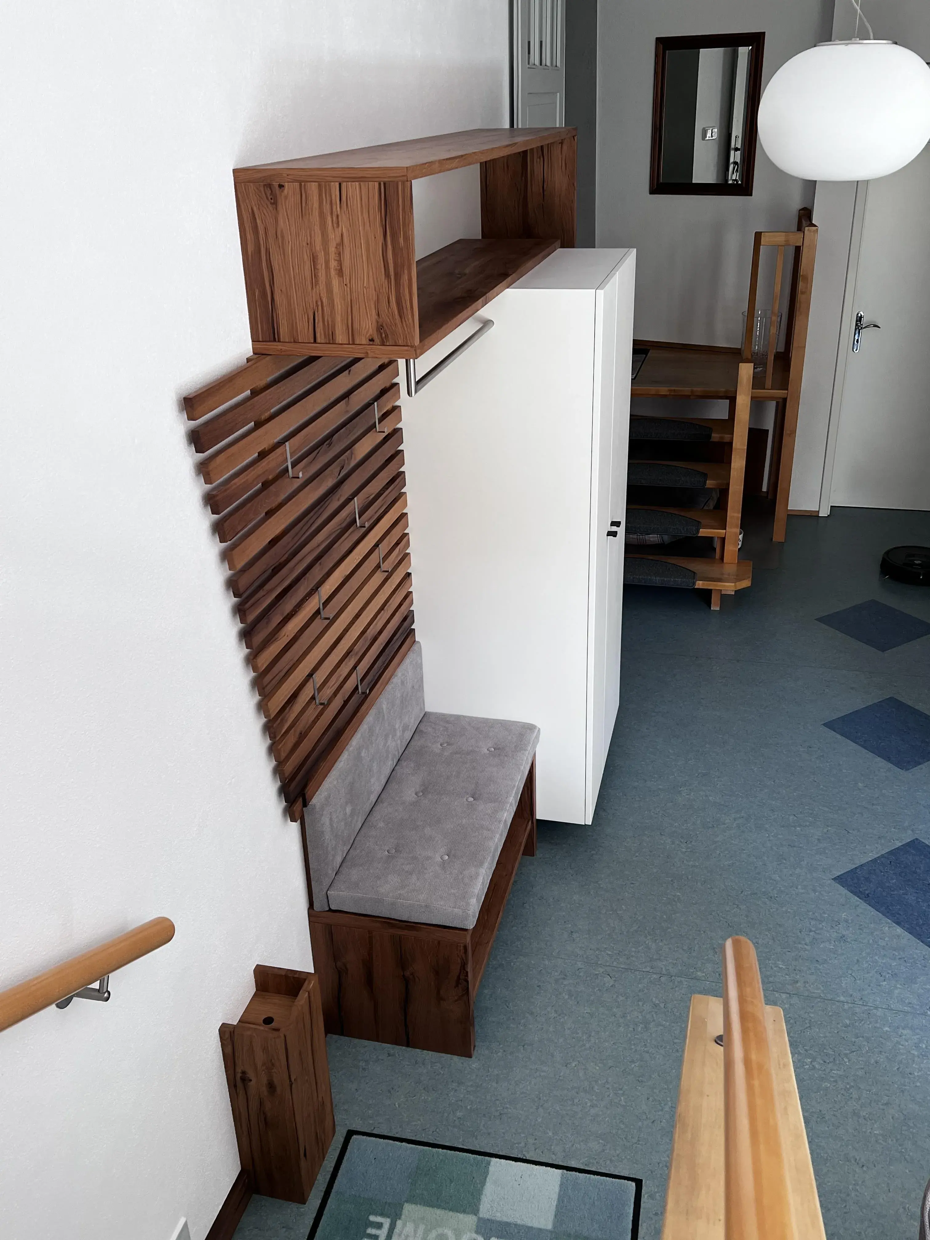 Holzgarderobe mit Bank und weißem Schrank in einem modernen Flur