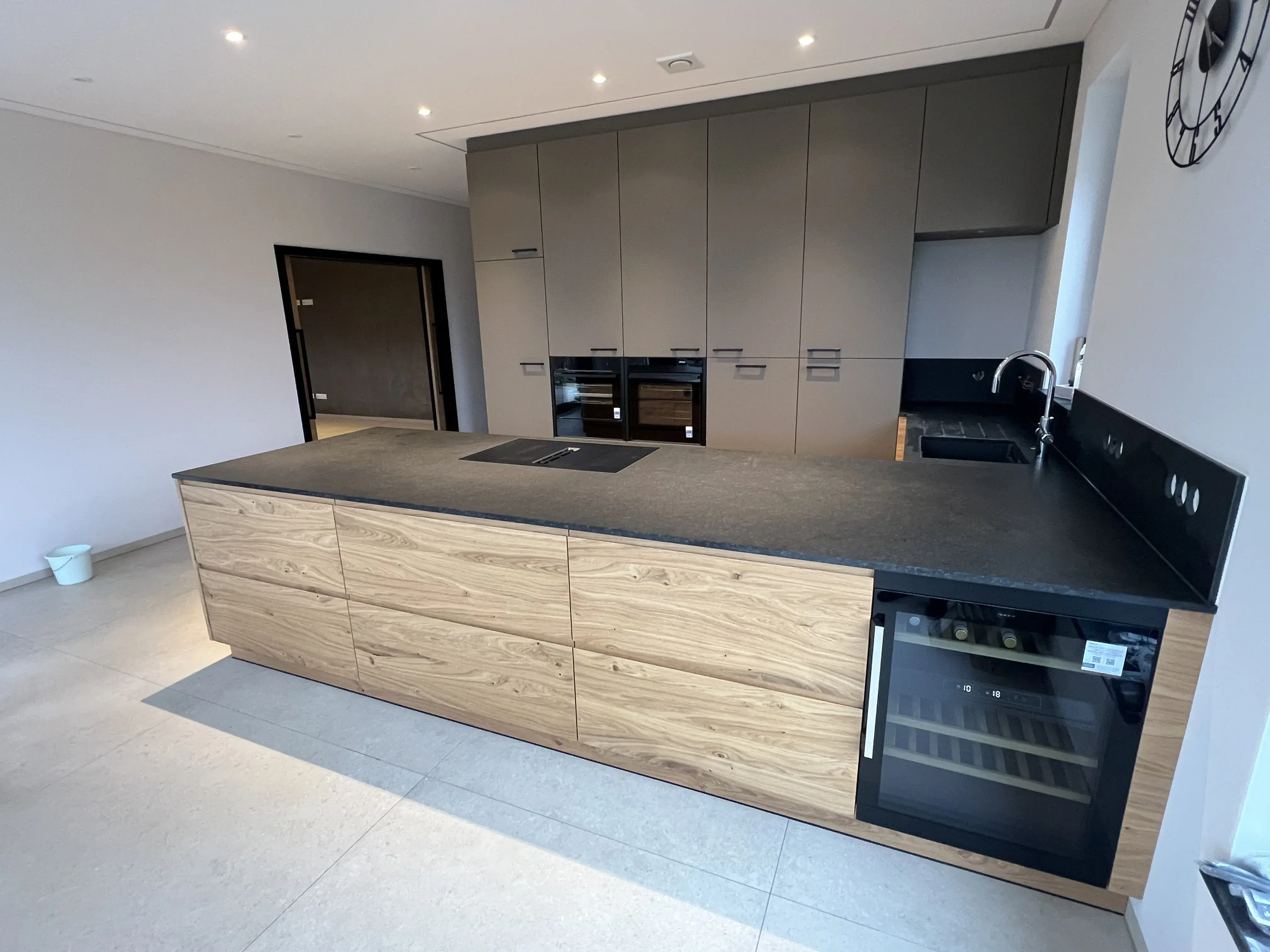 Moderne Küche mit schwarzer Arbeitsplatte, Holzfronten und Einbaugeräten.
