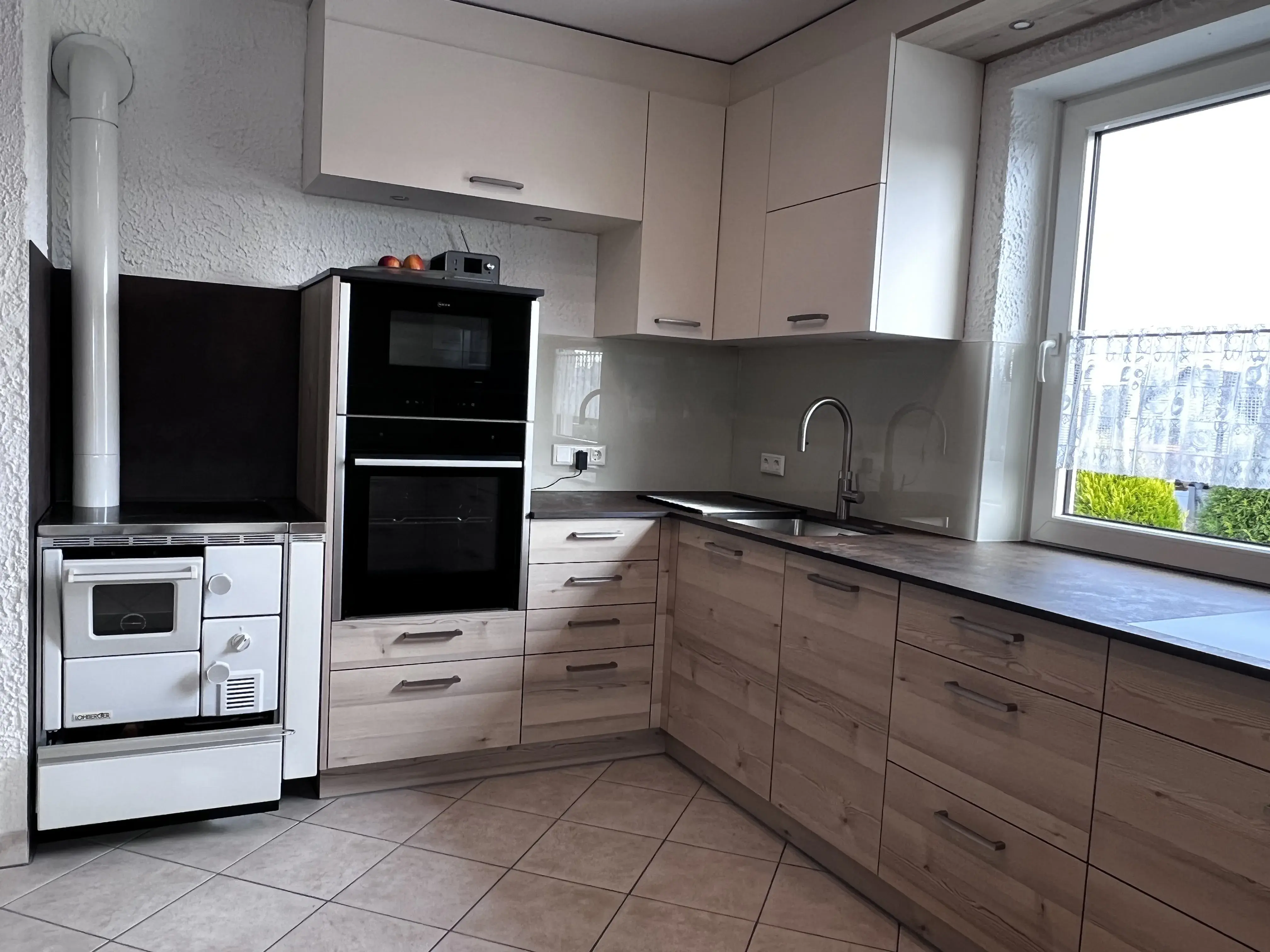 Moderne helle Küche mit Eck-Arbeitsplatte, Herd und großem Fenster