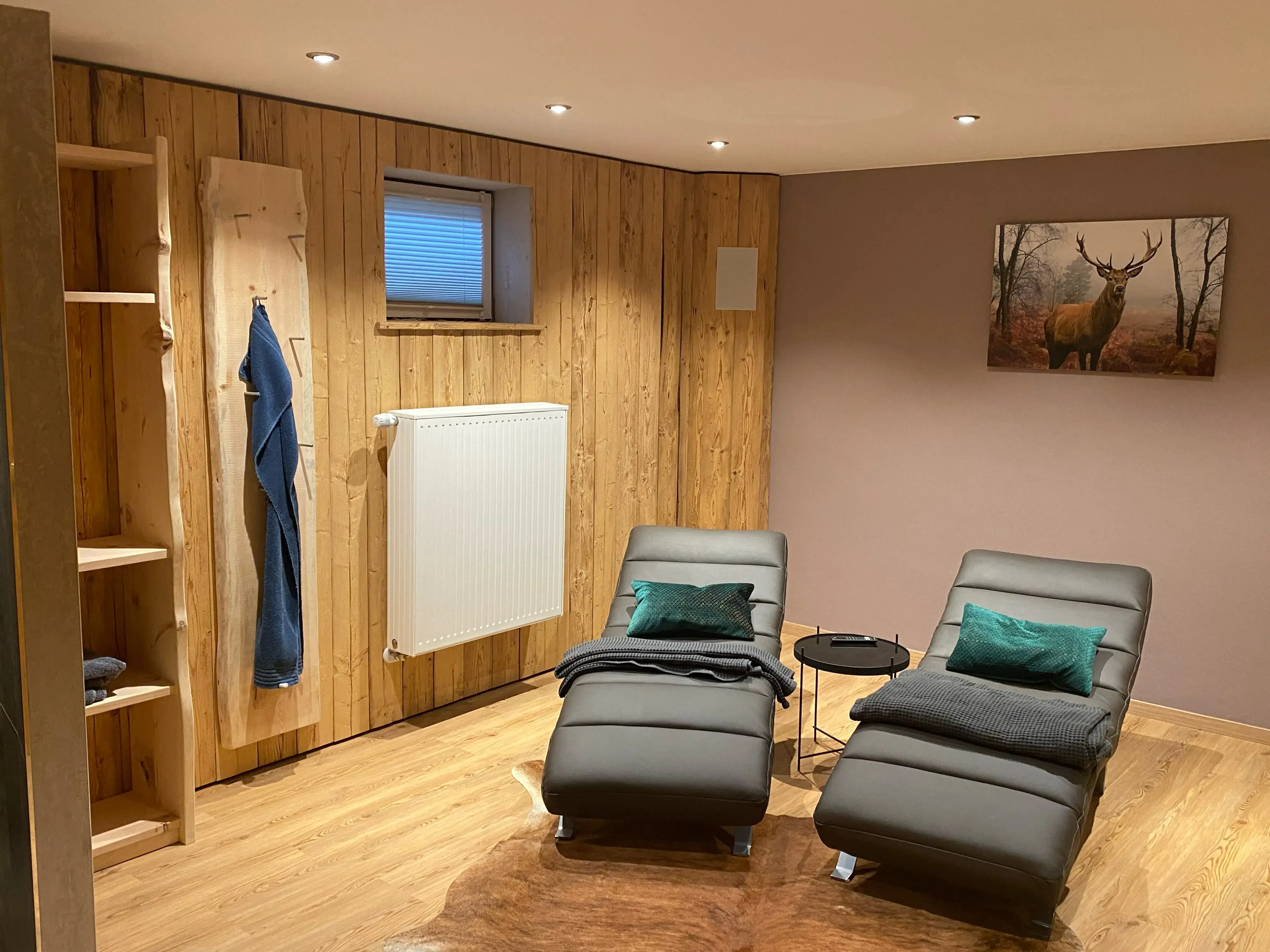 Gemütlicher Raum mit zwei Liegesesseln, Holzverkleidung und Hirschbild an der Wand.