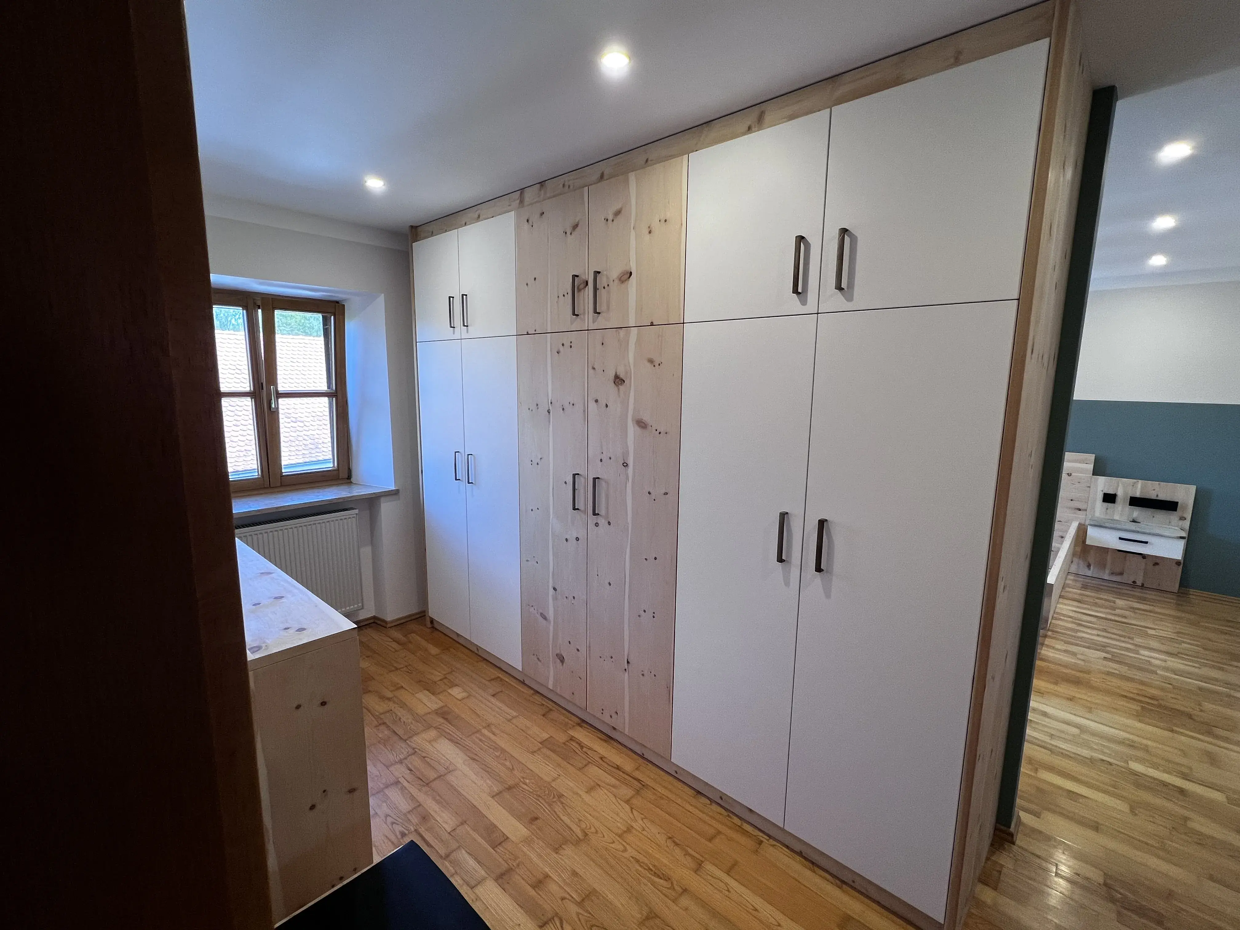 Heller Raum mit großem, weißen Einbauschrank und Holzboden.
