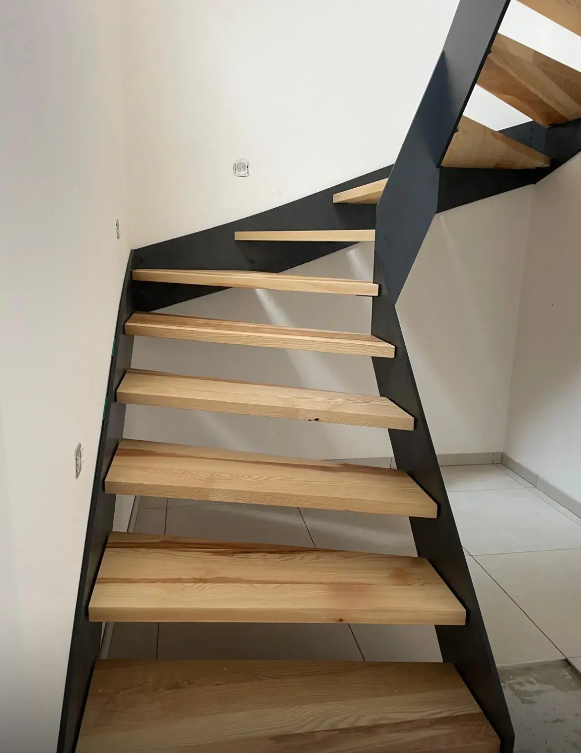 Moderne Holztreppe mit schwarzem Metallgestell in einem hellen Flur