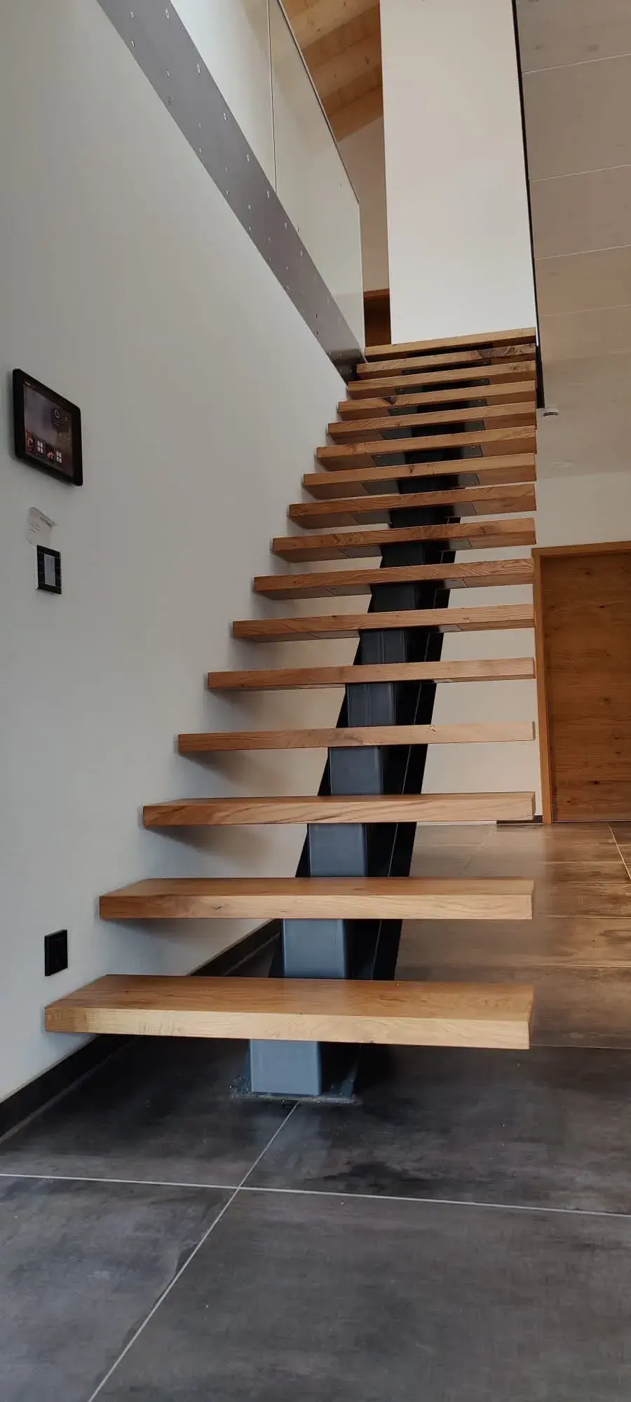 Moderne Holztreppe mit offenen Stufen in einem hellen Innenraum.