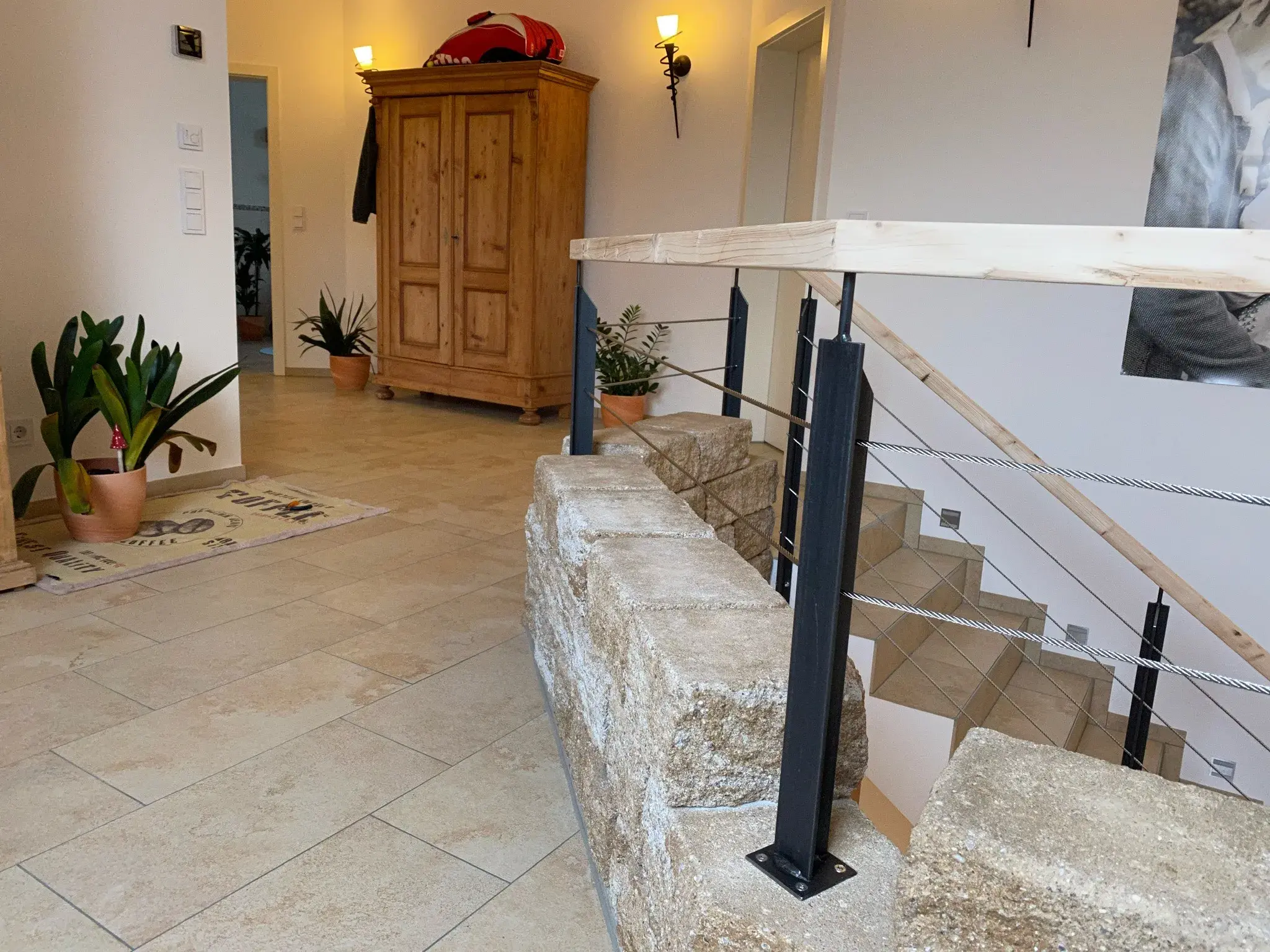 Helle Diele mit Naturstein-Treppe, Holzgarderobe und Zimmerpflanzen.
