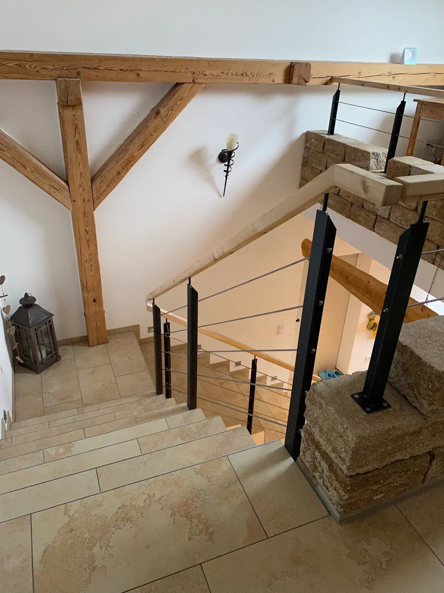 Treppe mit Steinfliesen und Holzgeländer in modernem, hellen Innenraum