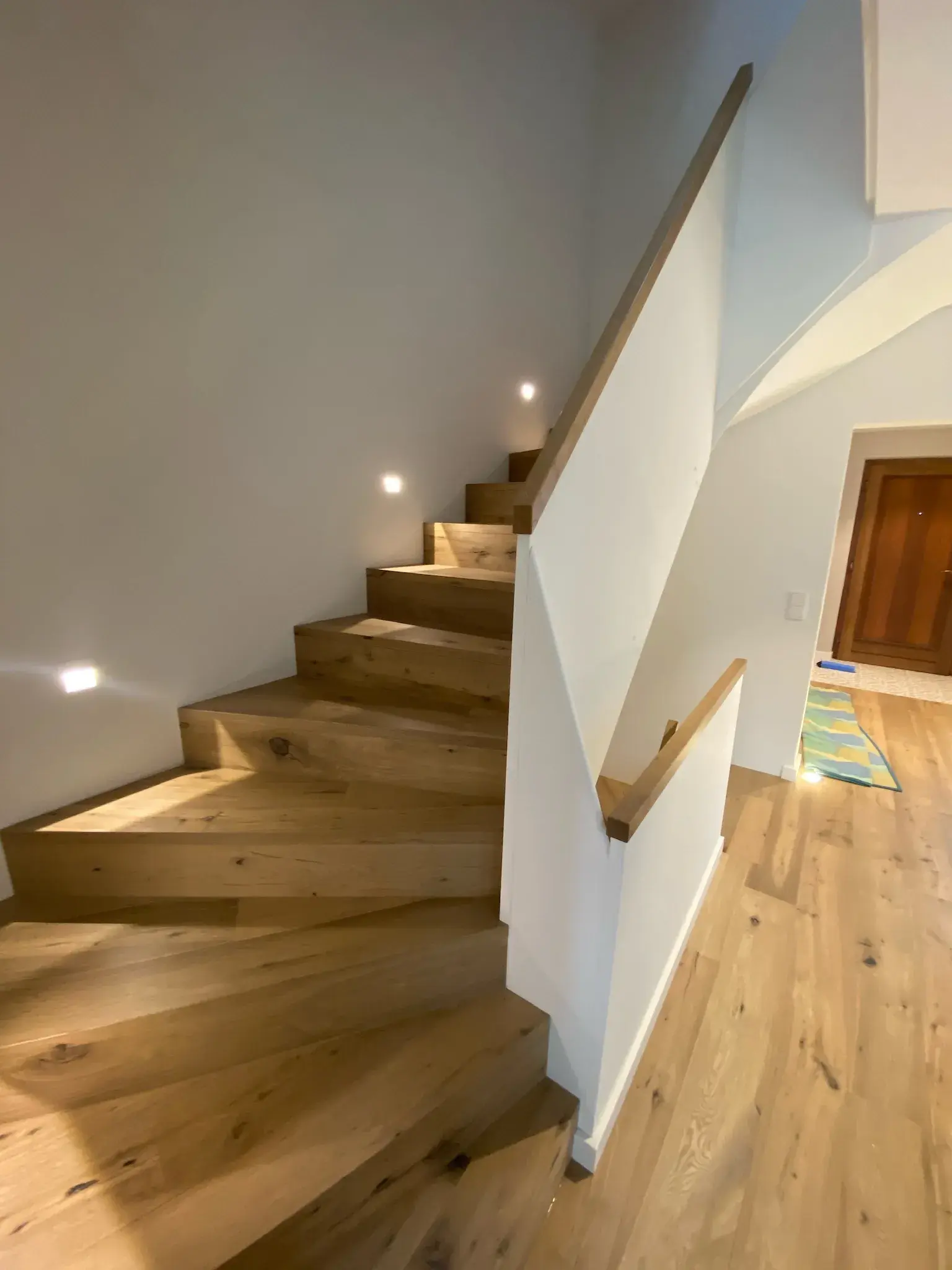 Holztreppe in modernem Haus mit eingebauten Wandlichtern.