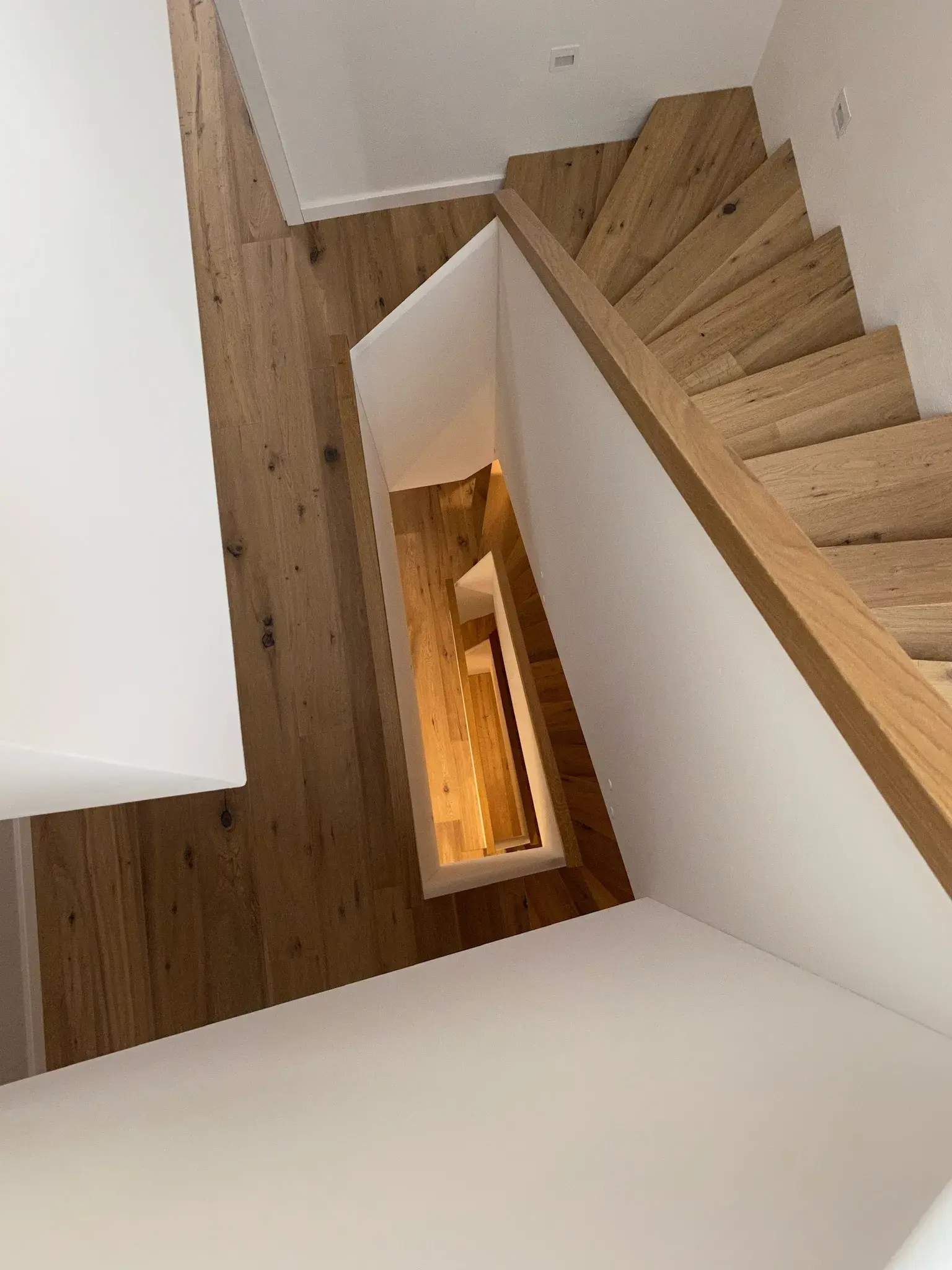 Holztreppe in modernem, weißem Haus, Blick von oben nach unten.