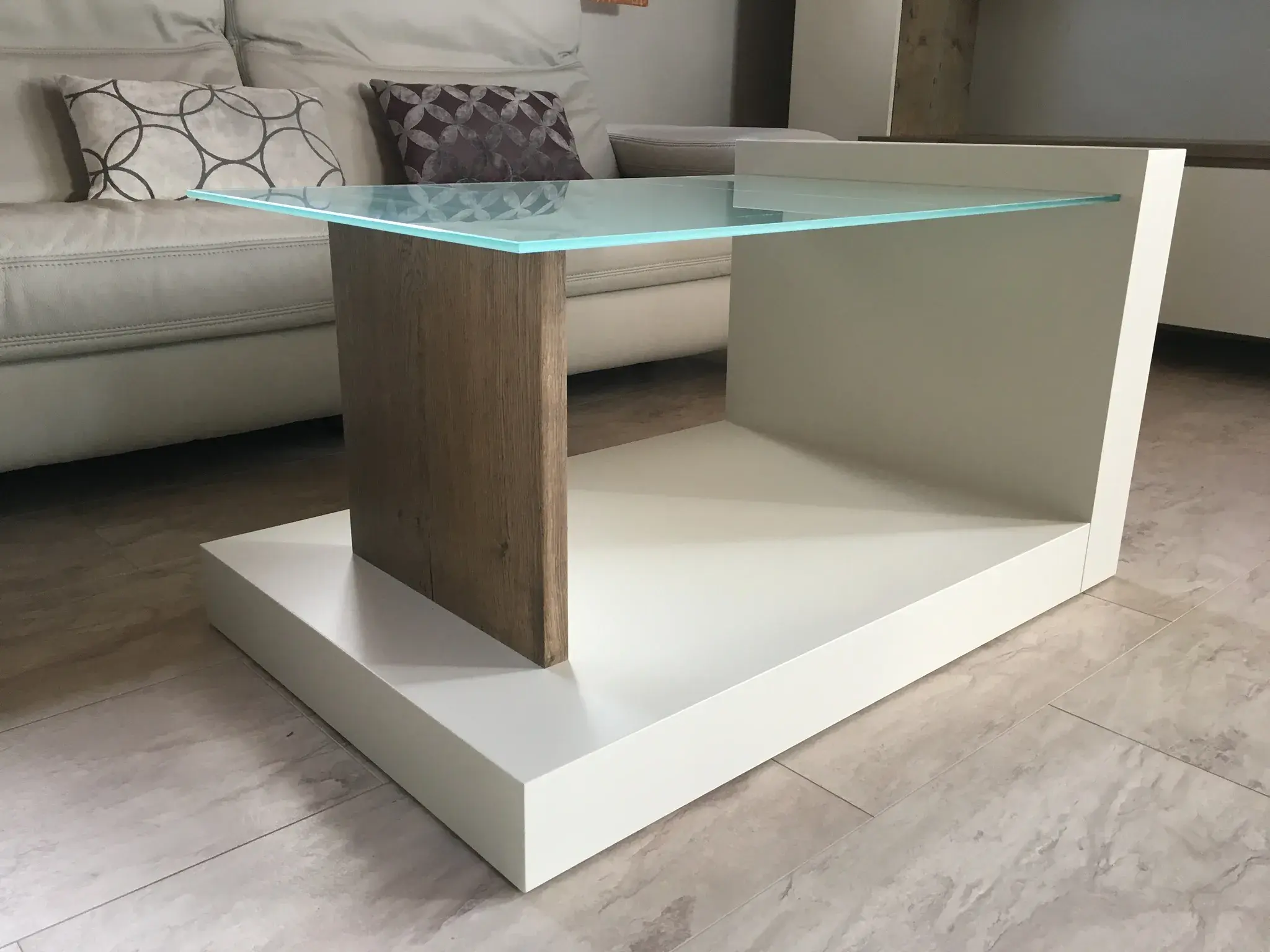 Moderner Couchtisch mit Glasplatte und Holzdetails in hellem Wohnzimmer