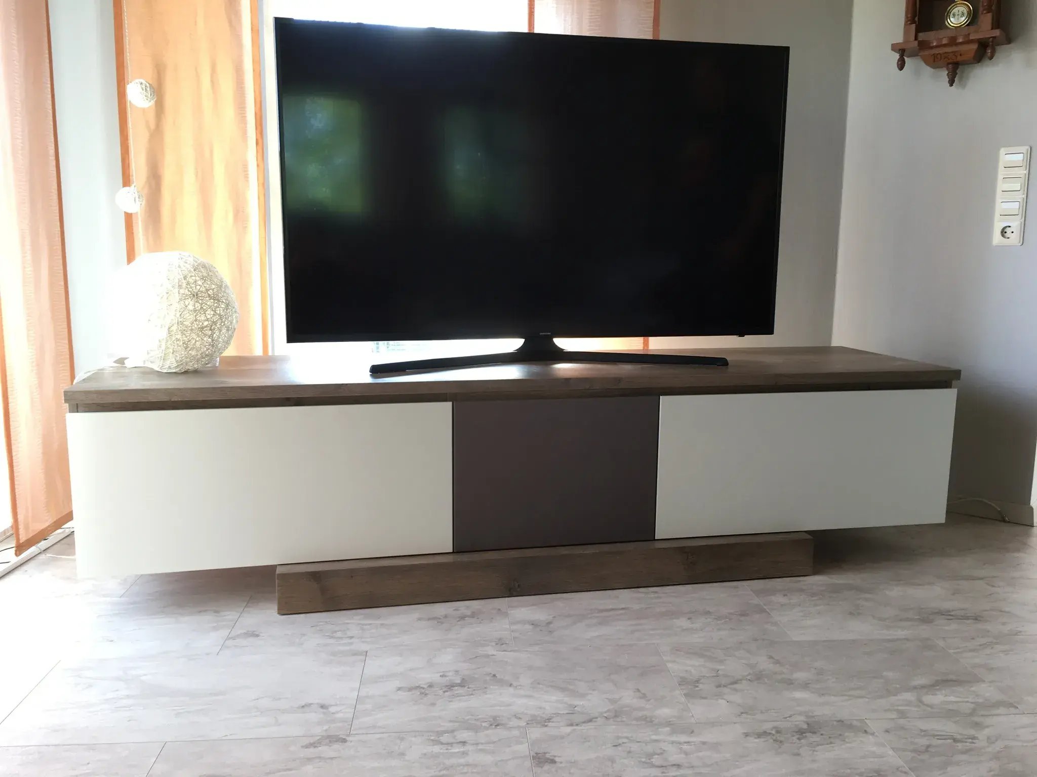 Flacher Fernseher auf modernem Sideboard in einem hellen Wohnzimmer